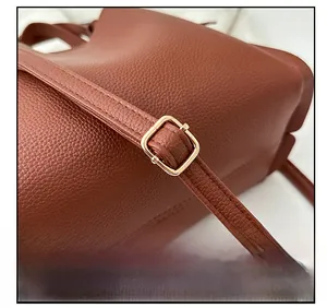 Détail de la bandoulière réglable et boucle en métal doré sur sac seau en cuir marron