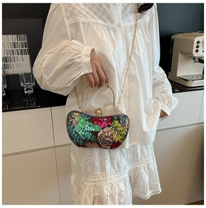 Détail d'une pochette à paillettes multicolores avec poignée dorée et fermoir perle
