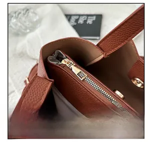 Détail macro du sac seau en cuir marron avec fermeture éclair métallique et boucle magnétique
