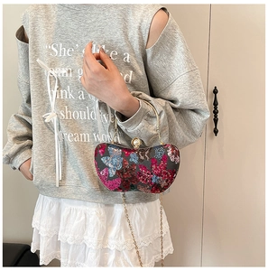 Détail de la broderie papillon en paillettes sur sac de soirée avec fermoir perle