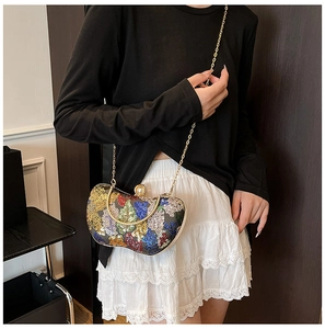 Détail de paillettes colorées et fermoir perle sur une pochette vintage à poignée dorée