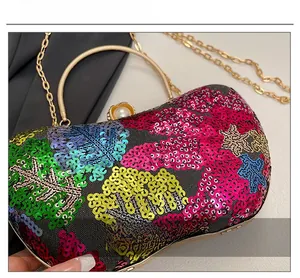 Détails des paillettes colorées et du fermoir perle sur un sac de soirée avec chaîne dorée