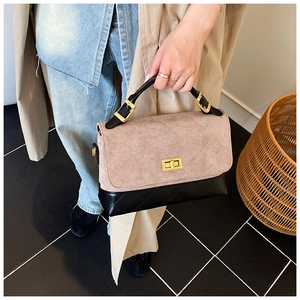 Detail of khaki suede and black leather patchwork bag with classic quilted stitching