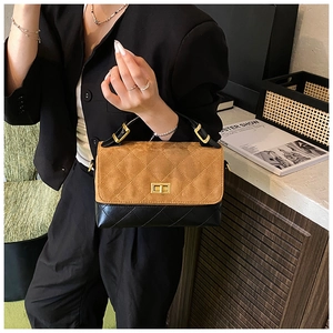 Macro detail of brown suede and black leather quilted bag with gold twist lock