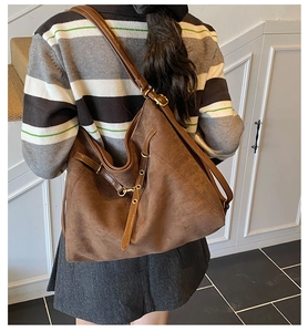 Détail d'un grand sac cabas en daim marron avec cordon et bandoulière réglable