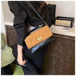 Detail of two-tone quilted bag featuring brown suede, black leather, and gold twist lock