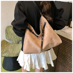 Gros plan sur la texture en daim marron et les boucles dorées de ce grand sac rétro