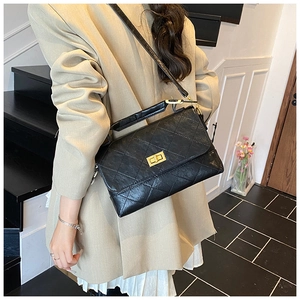 Classic black quilted leather crossbody bag with gold buckle on elegant female model