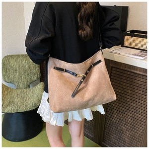 Détail du grand sac cabas en daim kaki avec lanières en cuir porté par un mannequin chic