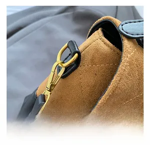 Detailed close-up of premium gold lobster clasp on brown quilted suede shoulder bag