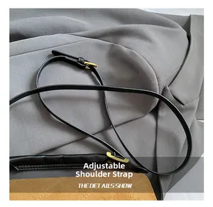 Detail of adjustable black leather strap with gold metal buckle on suede quilted bag