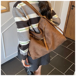Détail du sac cabas vintage en daim marron avec boucles en laiton et lanières en cuir