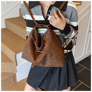 Vue détaillée d'un sac hobo en daim marron avec des lanières en cuir et des boucles