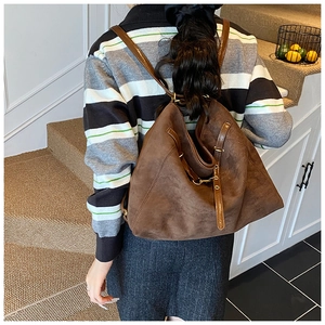 Détail d'un sac à dos vintage en daim marron avec fines bretelles sur un mannequin