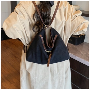Détail d'un sac à dos en toile noire avec des lanières en cuir marron porté par un mannequin