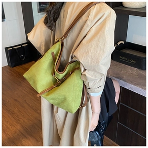 Détail du sac cabas en daim vert montrant la bandoulière en cuir brun et boucle dorée