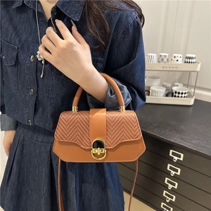Sac trapèze marron en cuir et tissage avec fermoir doré présenté dans un décor de vie
