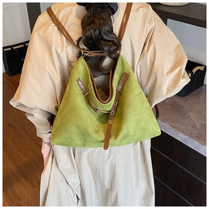 Détail du sac à dos en daim vert avec lanières brunes porté au dos du mannequin