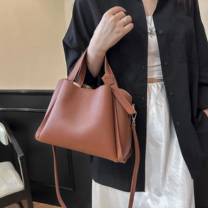 Sac seau en cuir caramel avec poignée supérieure et bandoulière réglable sur modèle