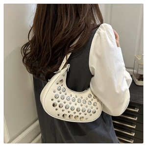 Detail of crescent shoulder bag featuring silver rivets and pearl embellishments on leather