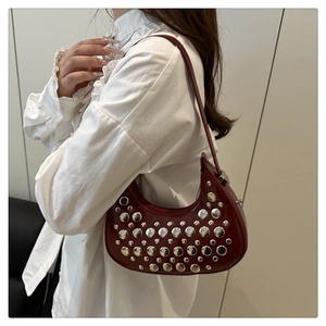 Detail of burgundy hobo bag with polished leather and decorative silver metal rivets