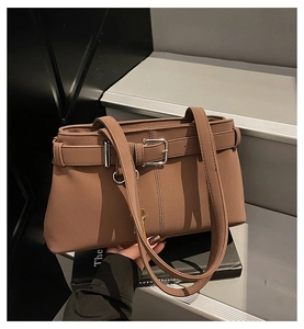 Detail of vintage brown leather underarm bag featuring silver buckle and matte finish