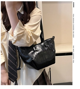 Detail of black glossy wax leather tote bag texture with natural wrinkles and shoulder strap