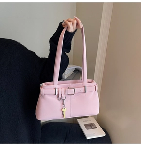 Pink matte leather baguette bag featuring belt buckle detail and a golden key pendant