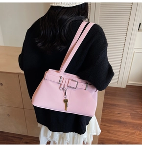 Close-up of pink PU leather shoulder bag with belt buckle and gold key pendant