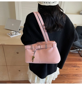 Detail of pink PU leather underarm bag with decorative belt and golden key charm