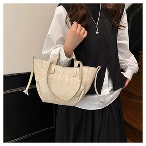 Close-up of cream glossy tote bag with vertical stitching and decorative side ties