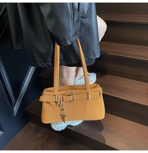 Detail of yellow vintage leather shoulder bag with decorative buckle and key charm