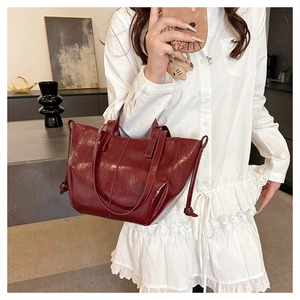 Detail of burgundy vintage tote bag showing glossy oil wax leather and side strap accents