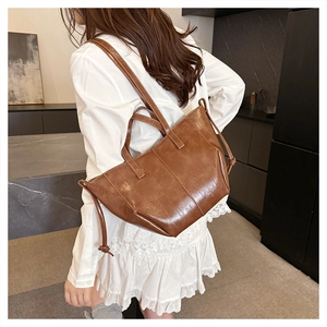 Brown leather tote bag side view on model showing spacious wing shape design