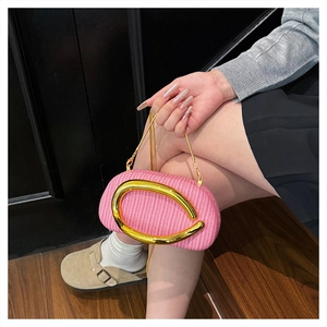 Detailansicht der rosa Webstruktur und des runden Goldgriffs an einer Box-Abendtasche
