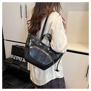 Model wearing a black glossy pleated tote bag with double handles for a stylish commute