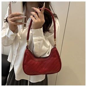 Close-up of red woven texture and golden metal buckle on a chic minimalist shoulder bag
