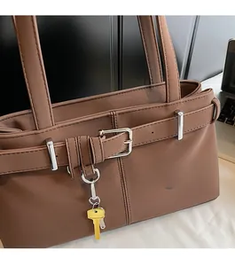 Detail of dark brown faux leather shoulder bag featuring silver buckles and polished hardware