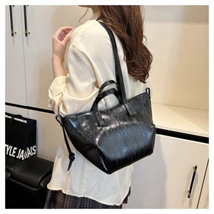 Close-up of black glossy textured leather tote bag with dual handle and shoulder strap
