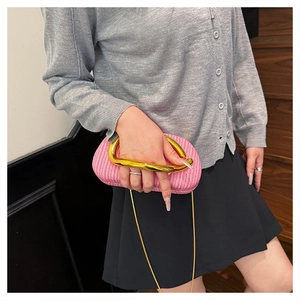 Nahaufnahme der leuchtend rosa geflochtenen Clutch mit goldenem Metallringgriff