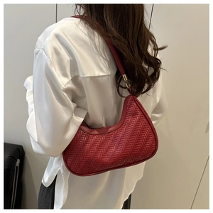 Vue détaillée d'un sac lune tressé rouge porté par un mannequin sur un fond blanc épuré