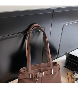 Detail of comfortable shoulder straps and silver metal buckles on a dark brown tote bag