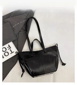 Close-up of black tote bag with rectangular embossed texture and drawstring detail