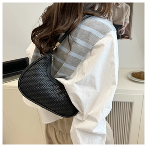 Modella che indossa una borsa a tracolla intrecciata nera con camicia bianca