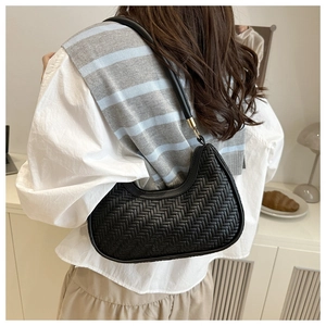 Detail of black woven crescent bag featuring faux leather texture and gold buckle accents