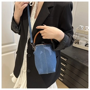 Détail d'un sac en denim rétro avec fermoir en métal vintage et poignée en cuir marron