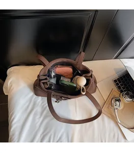 Spacious interior of brown faux leather shoulder bag holding daily essentials like umbrella