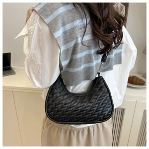 Détail du sac croissant noir tressé avec motif à chevrons et large bandoulière souple