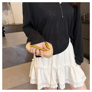 Detailaufnahme der beigen gewebten Handtasche mit goldenem U-förmigem Metallgriff