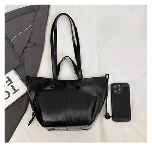 Size comparison of large black leather tote bag showing spacious capacity with a phone